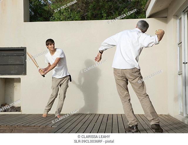 Father and son playing cricket on patio