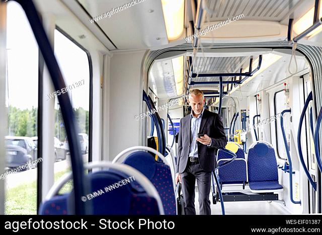 Male professional using smart phone in tram