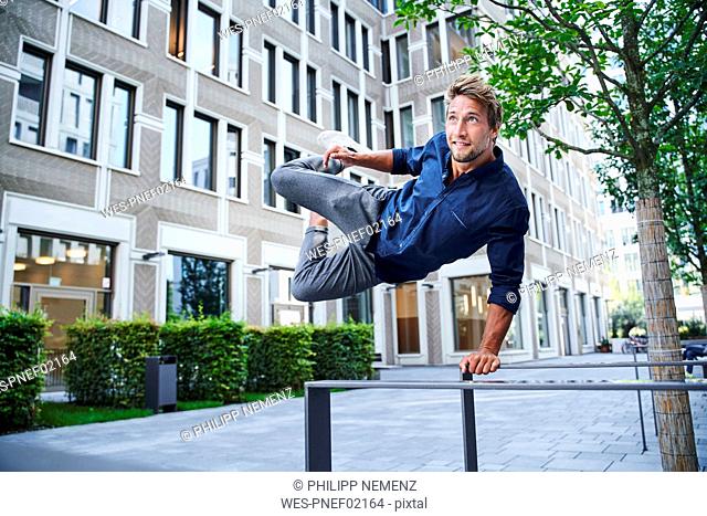 Young man jumping over railing in the city