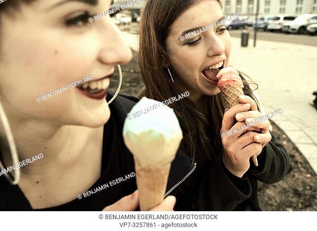 two women eating ice cream during warm winter day, in city Cottbus, Brandenburg, Germany