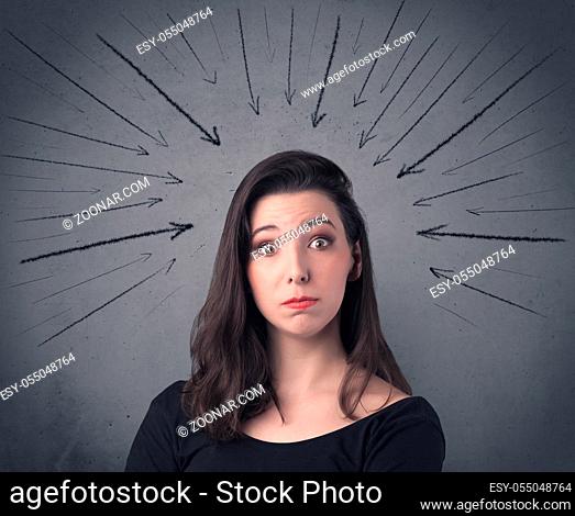 A teenage student girl under pressure while making happy face expressions illustrated with black arrows pointing at her head on the wall blackground concept
