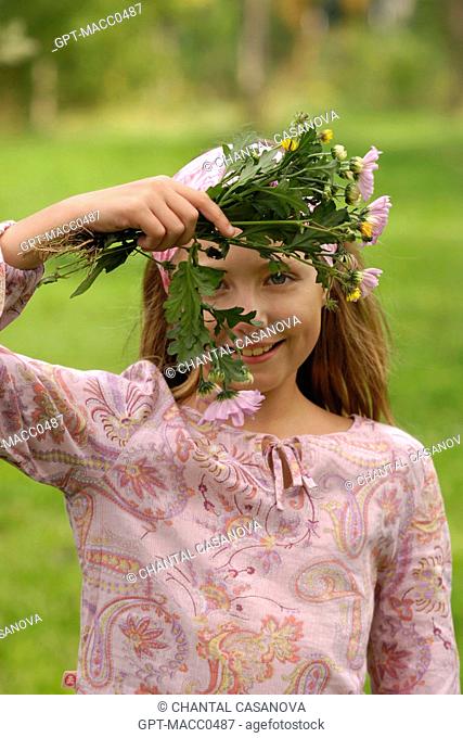YOUNG TEN-YEAR-OLD GIRL PICKING FLOWERS IN THE COUNTRYSIDE