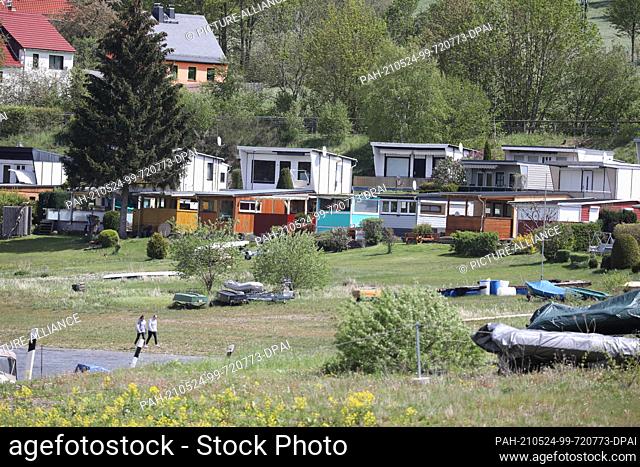 23 May 2021, Thuringia, Saalburg: Holiday bungalows stand on the banks of the Bleilochtalsperre. Visitors take advantage of the beautiful weather on Whitsunday...