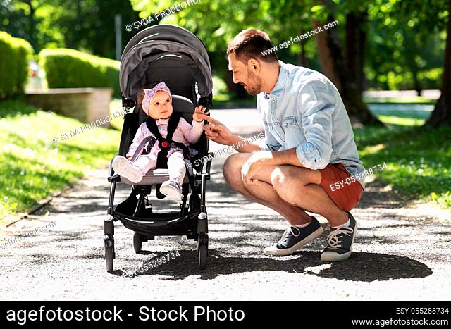 happy father with child in stroller at summer park