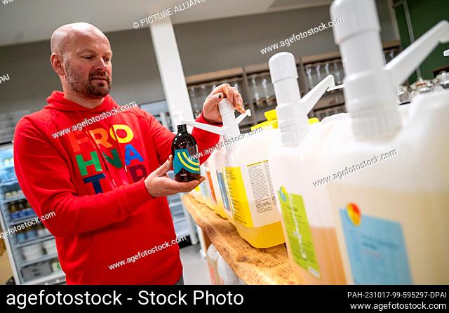 11 October 2023, Lower Saxony, Reppenstedt: Malte Melloh, founder of the unpackaged store ""FrohNatur, "" bottles washing lotion