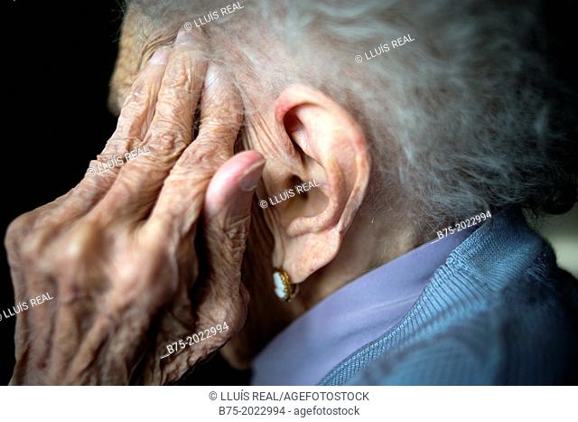 Portrait of a centennial woman in a elderly people home, hand covering her face