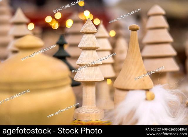 16 December 2023, Brandenburg, Leuthen: Wooden Christmas decorations on a stall at a small Advent market. Advent and Christmas markets are also held in many...