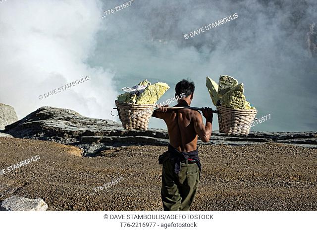 Miner carrying a heavy load of sulphur at the Kawah Ijen volcanic crater, Java, Indonesia