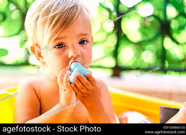 Little child chews on a rubber duck. High quality photo