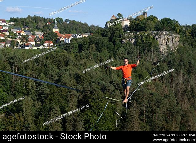 24 September 2022, Saxony, Hohenstein: The slackline runner Gregor Lawrenz runs at the Highline - and family festival on a 360 meter long rope between the...