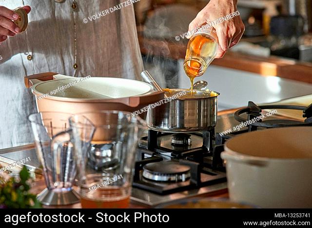 Woman's hand pours coconut syrup from a glass bottle into a stick cassar roll