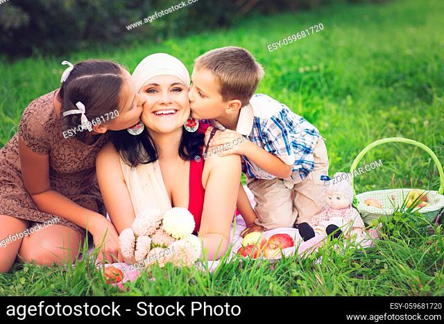 beautiful mother with son and daughter having picnic on grass. oudoor shot