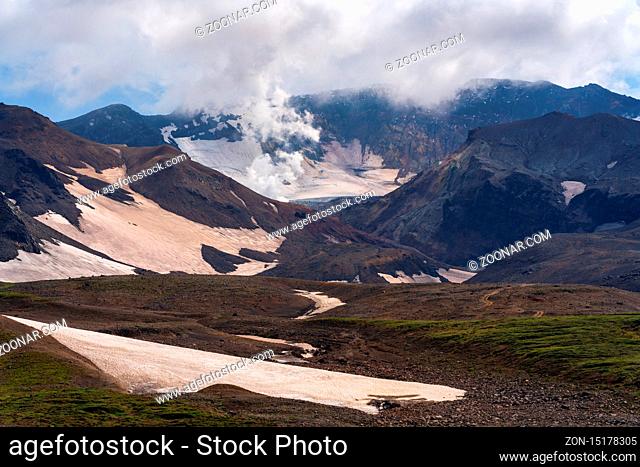 Autumn volcanic landscape of Kamchatka Peninsula, view of cone active Mutnovsky Volcano geothermal clouds eruption from crater - popular travel destinations for...