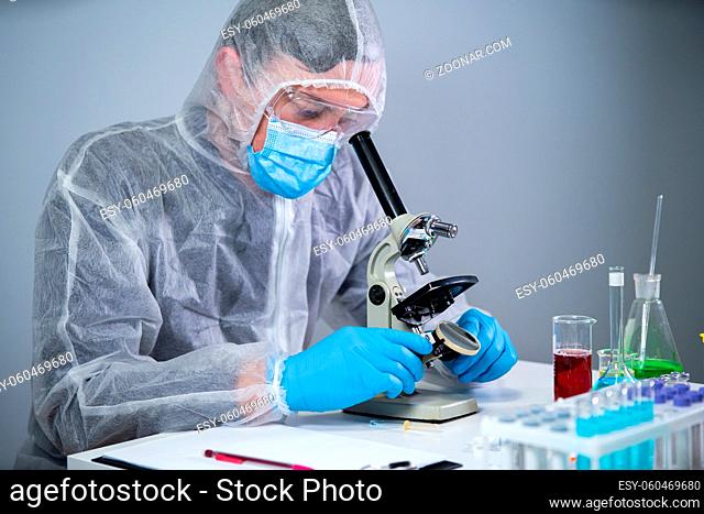 Pharmaceutical manufacturers developing viral medicines by inventing best ingredient. Scientist wearing personal protective equipment with face mask watching...