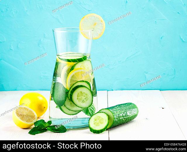 Infused detox water with cucumber, lemon and mint in glass bottle on white table. Diet, healthy eating, weight loss concept. Copy space