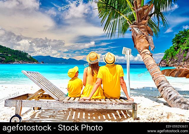 Family on beautiful Petite Anse beach, young couple with three year old toddler boy sitting on sun bed. Summer vacation at Seychelles, Mahe
