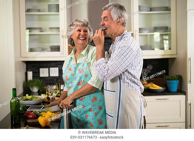 Playful senior couple enjoying while cooking in kitchen
