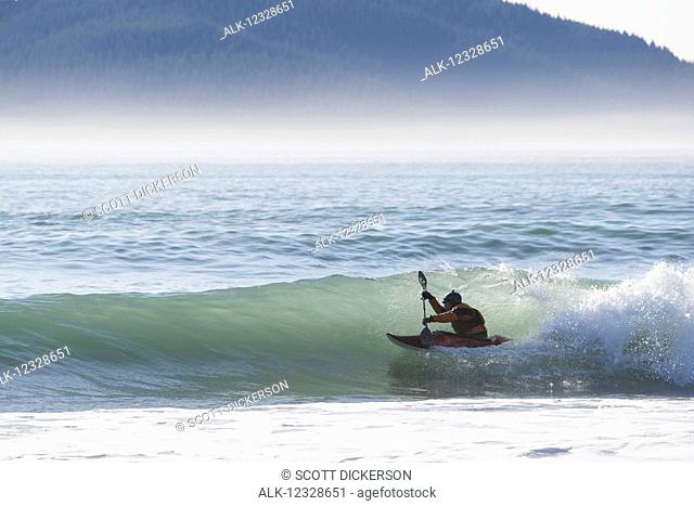 Person kayaking surfing along the Kenai Peninsula Outer Coast, South-central Alaska; Alaska, United States of America