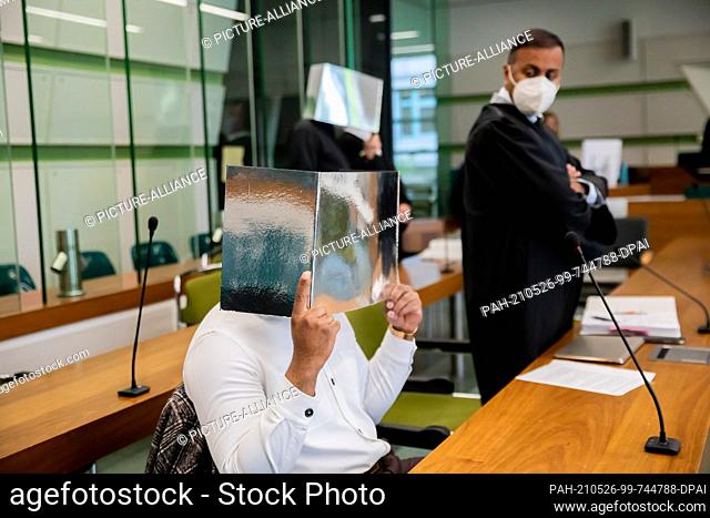 26 May 2021, Berlin: Two of the three defendants hold reflective cardboard in front of their faces at the beginning of the trial in the courtroom of the...