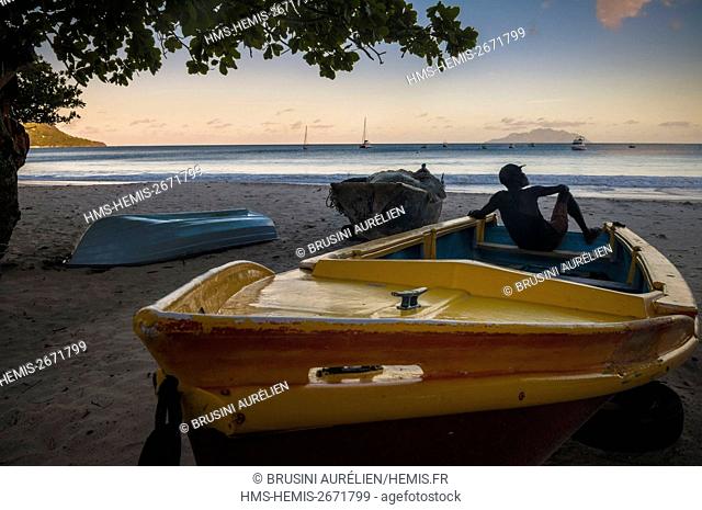 Seychelles, Mahe Island, Beau Vallon, old fisherman watching the ocean from the beach at sunset