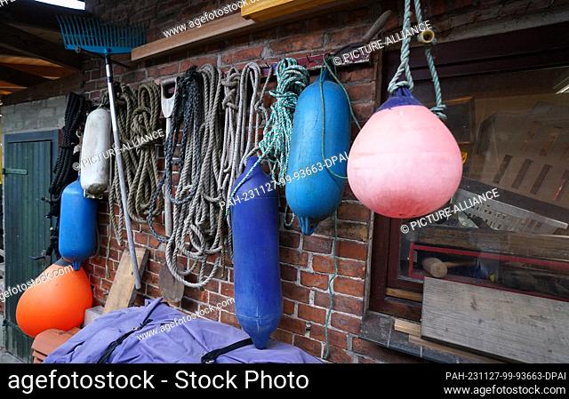 27 November 2023, Schleswig-Holstein, Lübeck: Nets, buoys and fenders hang from a house in the small fishing village of Gothmund on the River Trave