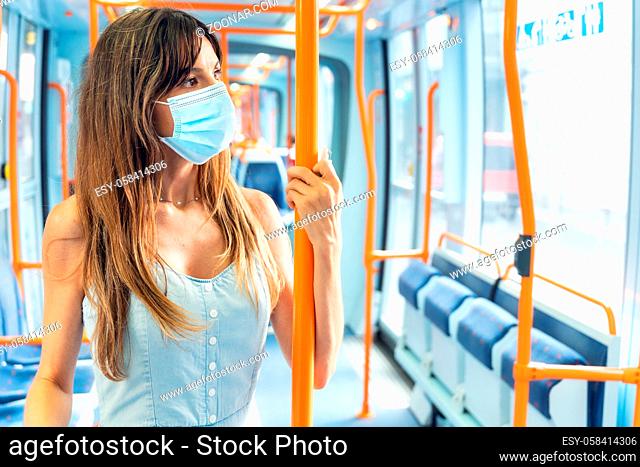 Woman with face mask traveling by tram during Covid-19 outbreak. High quality photo