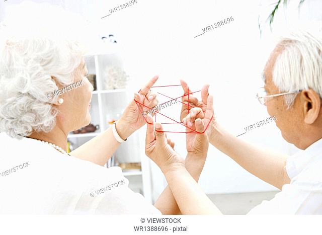 Happy elderly couple playing the game turned rope