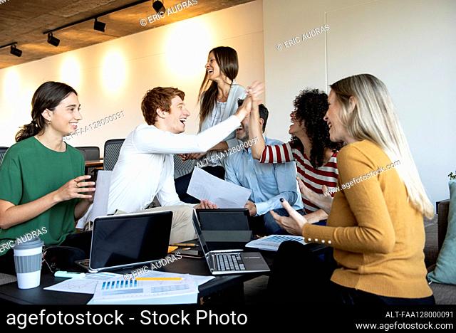 Colleagues giving high five at a group meeting