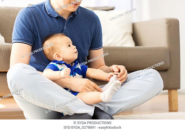 father with baby son sitting on floor at home