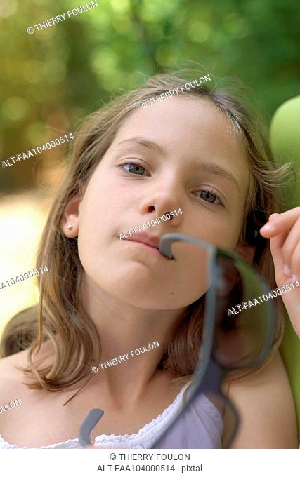 Girl holding sunglasses in her mouth, portrait