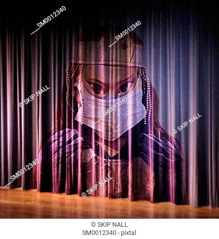 A stage curtain with the face of a scary doctor appearing on it