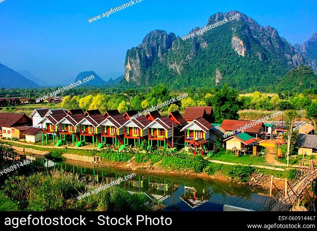 Row of tourist bungalows along Nam Song River in Vang Vieng, Vientiane Province, Laos. Vang Vieng is a popular destination for adventure tourism in a limestone...