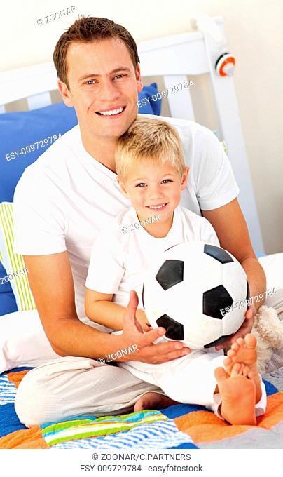 Close-up of a little boy and his father playing with a soccer ball