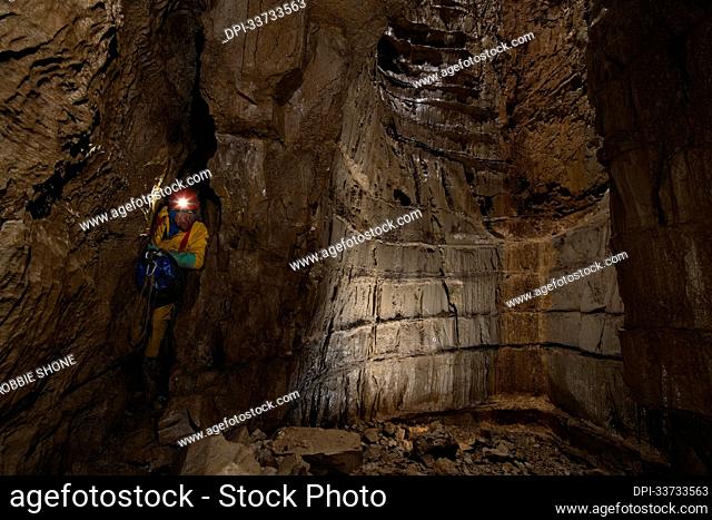 Expedition team member slides through a narrow slot, emerging at the base of another vertical shaft. Typically throughout the descent of the first third of...