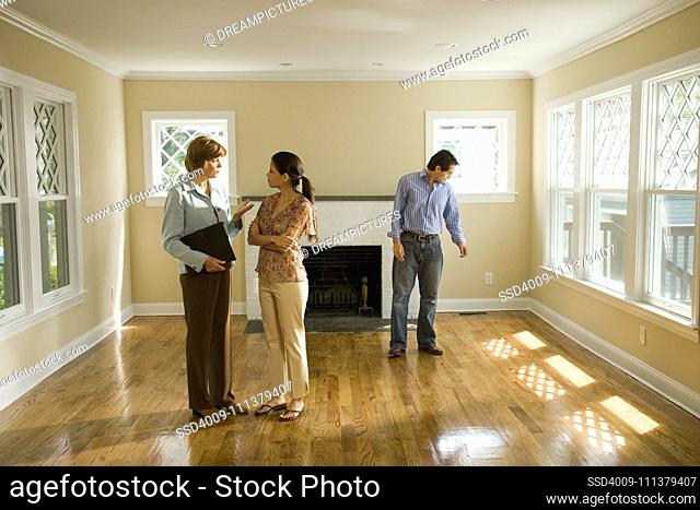 Hispanic couple talking to real estate agent in house
