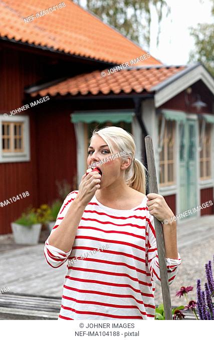 Woman eating apple in front of house