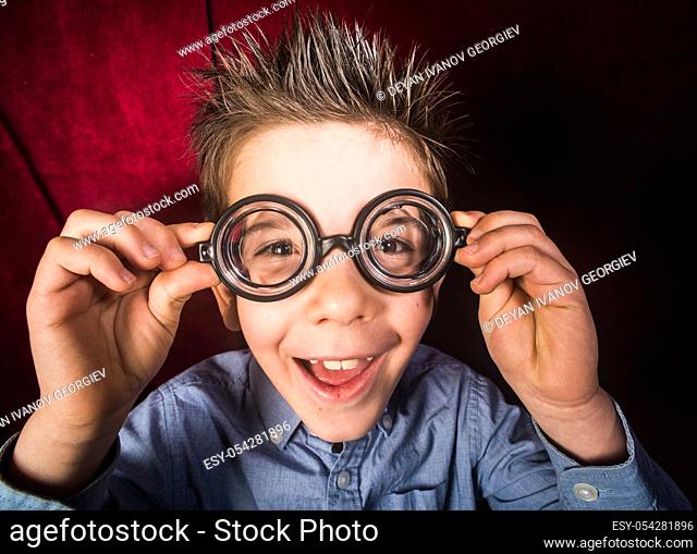 Smiled child with big glasses. Red curtain background