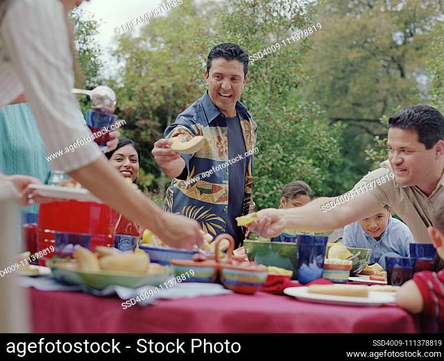 People reaching for food at a barbecue