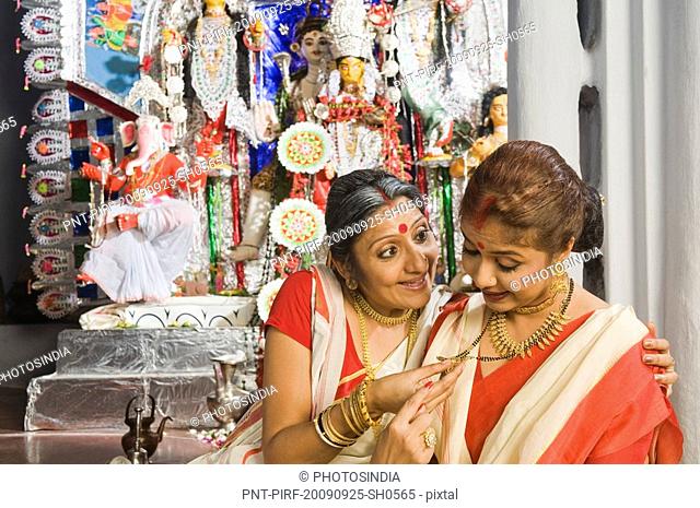 Woman admiring mangalsutra of her daughter-in-law
