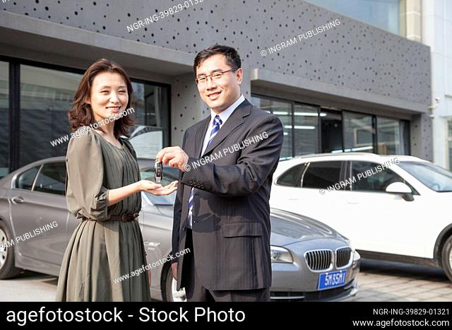 Businessman Handing Car Keys To Woman in Auto Repair Shop