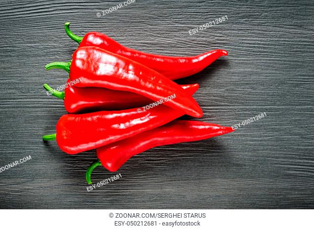 Heap of five ripe sweet red Kapia peppers on dark shale stone background, copy space