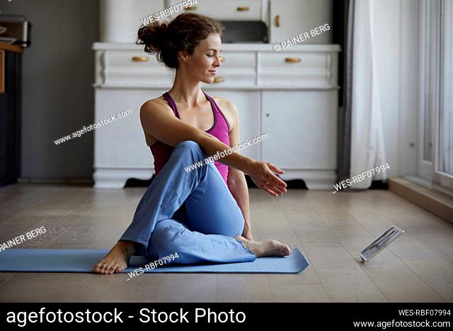 Woman watching digital tablet while practicing yoga at home