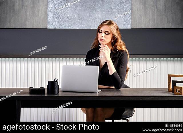 Young woman waiting for connection of online call in the office sitting behind the desk