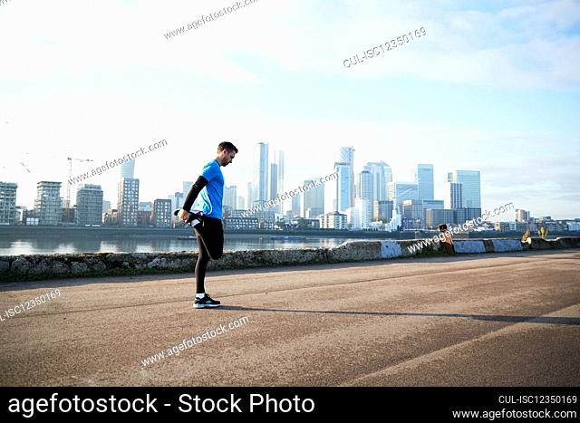UK, London, Jogger stretching with downtown skyline in background