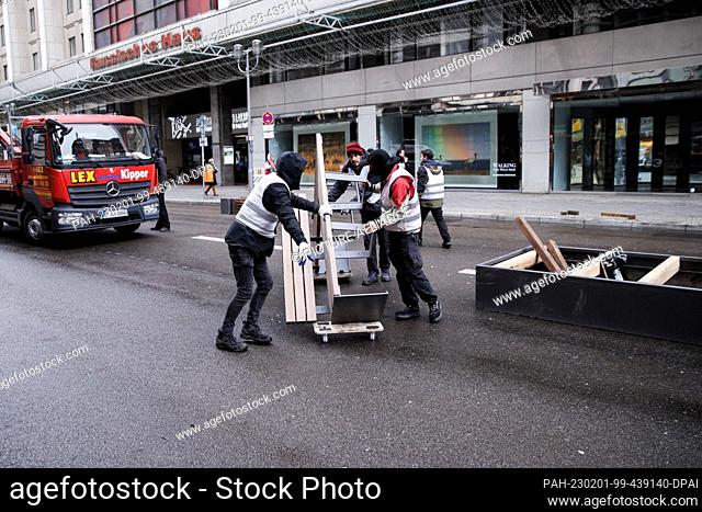 01 February 2023, Berlin: Employees of a planning office carry seating elements for benches on Friedrichstrasse. The section in question