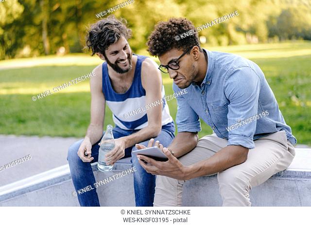 Two friends sitting in a skatepark
