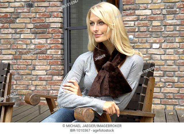 Portrait of a beautiful blond woman sitting outside and wearing a fake fur scarf