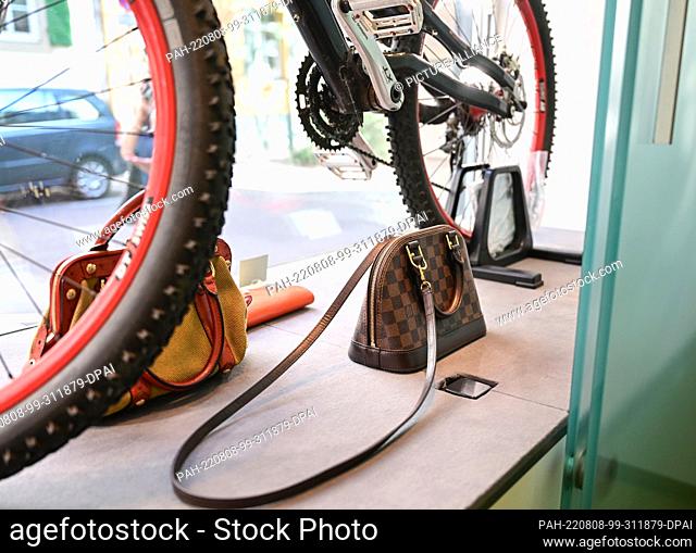 PRODUCTION - 02 August 2022, Baden-Wuerttemberg, Stuttgart: Luxury bags handed in for sale and a mountain bike stand in a shop window at the Städtische...