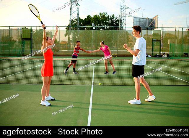 Mixed doubles tennis, players finished the game, outdoor court. Active healthy lifestyle, sport with racket and ball, fitness workout with racquets