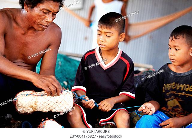 Portrait of a fisherman in Thailand teaching his children his work